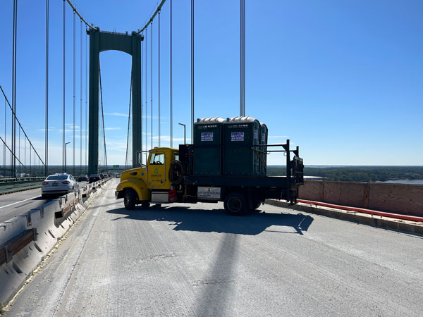 Complete Site Solutions truck hauling portable toilets over bridge